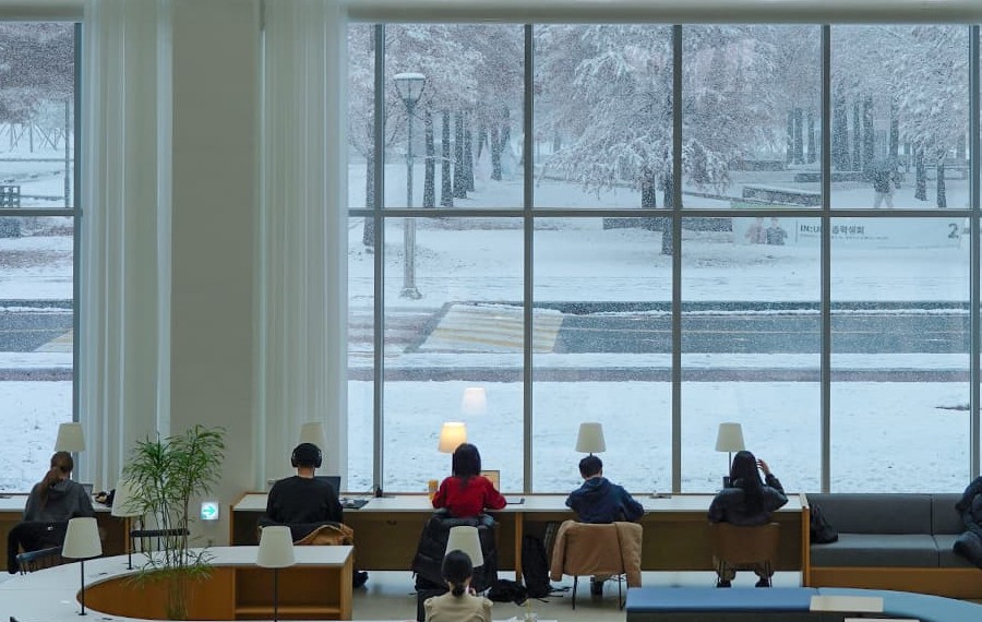 雪景色の窓際でPCに向かい勉強する学生たち（仁川大学 出願情報）